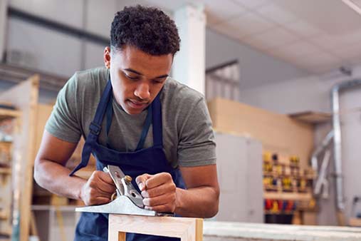 a man in an apron using a plane