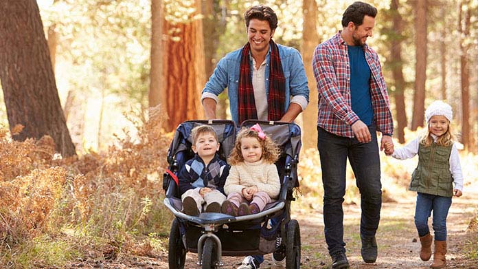 Two dads taking their children on a nature walk.