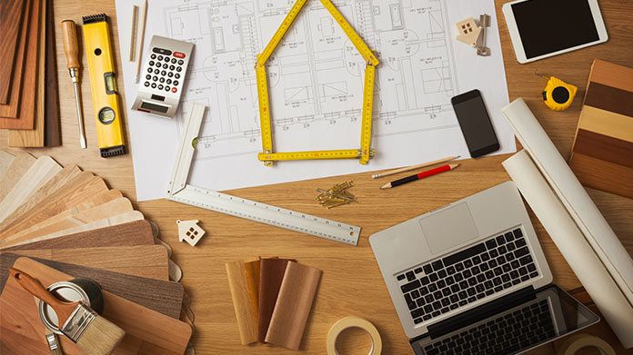 A desk filled with rulers, blueprints, and carpentry tools.